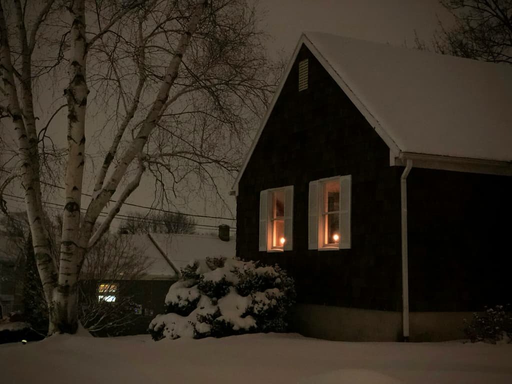 Home at dusk in winter with warm light in the windows